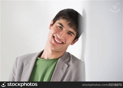 Mixed ethnicity handsome man leaning on white wall with editable copyspace