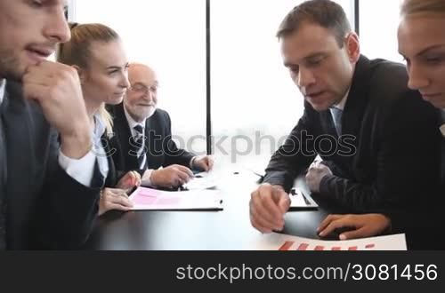 Mixed group of people at business meeting working together with documents and computers