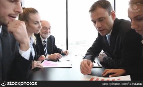 Mixed group of people at business meeting working together with documents and computers