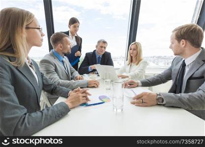 Mixed group of white collar workers at business meeting discuss documents. Workers at business meeting