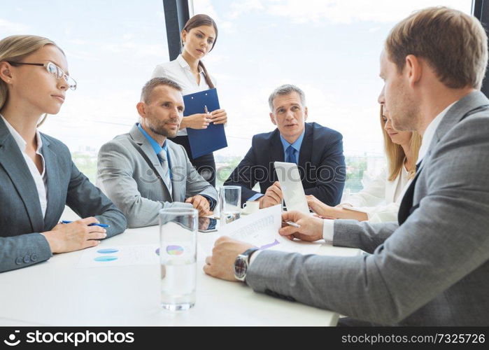 Mixed group of white collar workers in business meeting discuss documents. Workers in business meeting