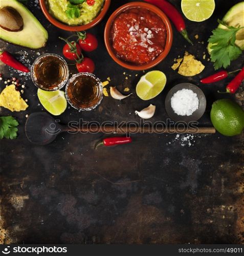Mixed mexican food background. Party food. Guacamole,nachos, salsa, peppers, tomatoes, avocado and tequila shots on a rustic table. Space for text. Top view. Tex-mex cuisine. Assorted appetizers. Food frame