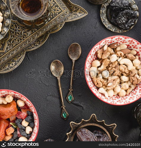 mixed nuts tea dried fruits metallic spoons black concrete backdrop