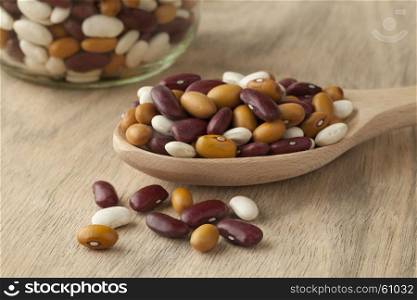 Mixed organic colorful beans on a wooden spoon