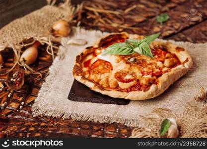 Mixed pizza with chicken, pepper, olives, onion, basil on pizza board. Close up view of baked homemade piza. Rustic pizza home made food.. Tasty pizza with vegetables and basil