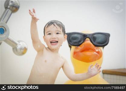 Mixed Race Boy Having Fun at the Water Park with Large Rubber Duck in the Background.