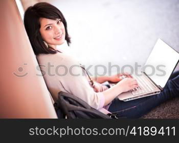 Mixed race college student working on laptop at campus