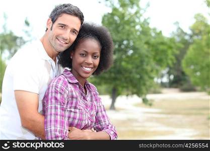 Mixed race couple hugging in the countryside
