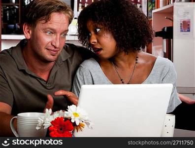 Mixed race couple in coffee house with laptop computer