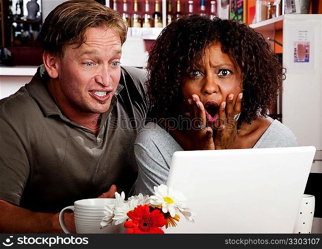 Mixed race couple in coffee house with laptop computer