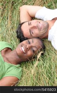Mixed race couple laying in a field