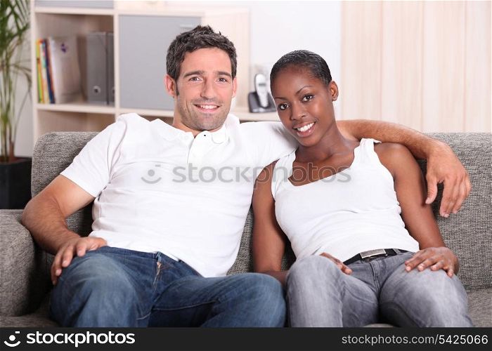 Mixed race couple sat on couch