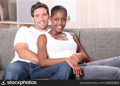 Mixed race couple sat on sofa