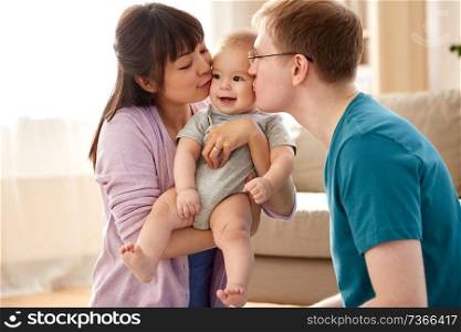 mixed-race family, parenthood and people concept - happy mother and father kissing their baby son at home. happy mother and father kissing baby son at home