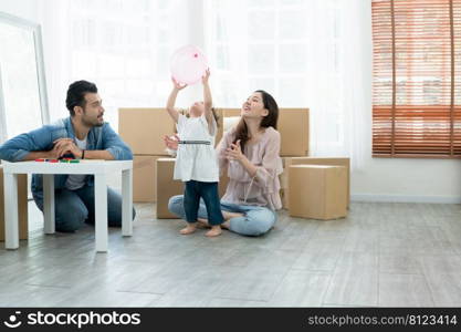 Mixed race family playing balloon together. Young Caucasian father with beard and Asian mother playing blocks toy and blow balloon with little cute daughter. Family celebrate move to new house