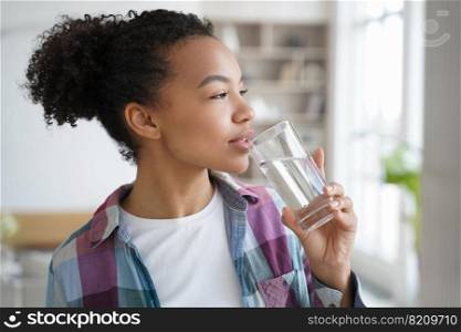 Mixed race girl drinking pure filtered water in the morning at home. Thirsty young woman holding glass of mineral aqua, enjoying fresh beverage. Healthy lifestyle, daily routine, body care concept.. Mixed race young girl drink pure water from glass at home. Healthy lifestyle, morning routine
