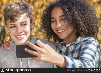 Mixed race group of two happy children teenagers, African American girl caucasian boy laughing together and taking selfie photograph on cell phone smartphone