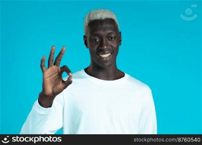 Mixed race man showing thumb up sign over blue background. Positive african guy smiles to camera. Winner. Success. Body language. Mixed race man showing thumb up sign over blue background. Positive african guy smiles to camera. Winner. Success. Body language.