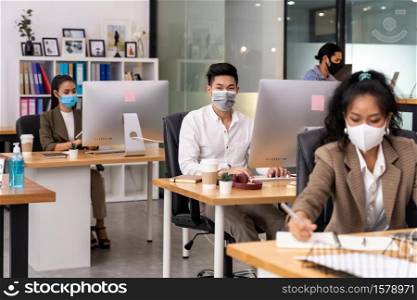 Mixed race of African black and asian business woman wear face mask working in new normal office with social distance to Group of business team people to prevent coronavirus COVID-19 spreading