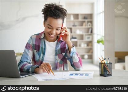 Mixed race teen girl school student talking on phone discusses homework with friend. Smiling schoolgirl, sitting at desk with laptop, making call, having mobile conversation while learning at home.. Smiling mixed race school girl student makes phone call, learning at home at desk with laptop