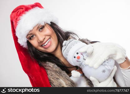 Mixed race woman in santa hat with little snowman.. Smiling cute woman in santa claus hat holding little snowman. Attractive mixed race african girl in studio on gray. Christmas season.