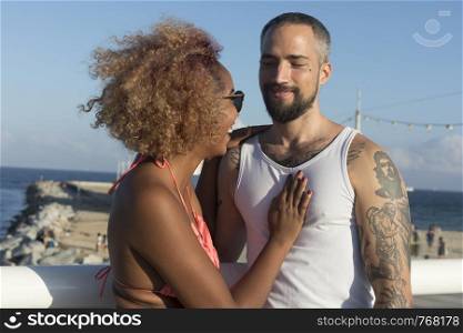 Mixed raced couple on sunny beach in summer vacation