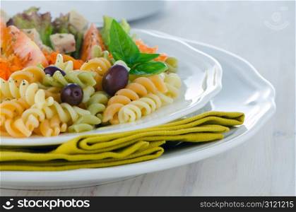 Mixed salad on a white plate and a white wood background.