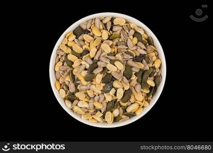 mixed seeds and nuts in ceramic white bowl on dark background