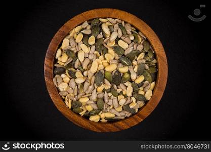 mixed seeds and nuts in wooden bowl on dark background