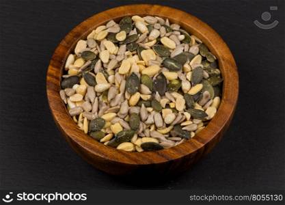 mixed seeds and nuts in wooden bowl on dark background