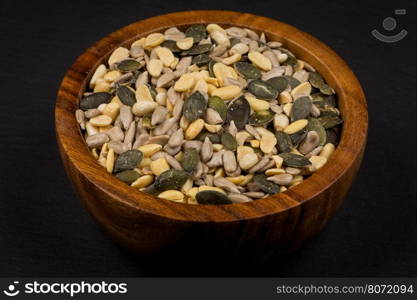 mixed seeds and nuts in wooden bowl on dark background