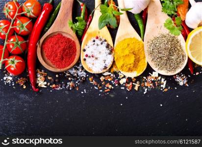 mixed spices with fresh vegetables on dark background