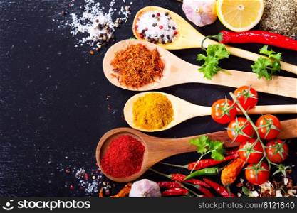 mixed spices with fresh vegetables on dark background