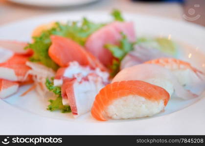 Mixed sushi and sashimi served on white plate