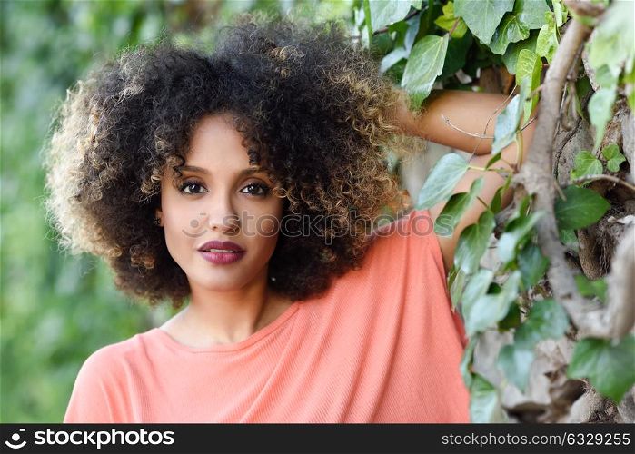 Mixed woman with afro hairstyle standing in an urban park