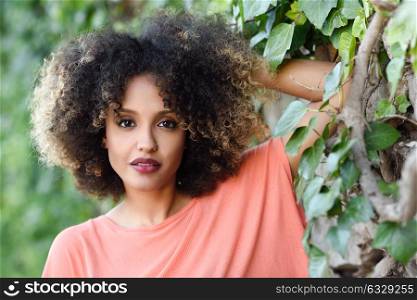 Mixed woman with afro hairstyle standing in an urban park