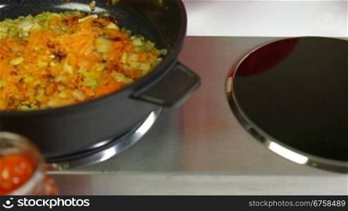 Mixing carrot and onion in frying pan