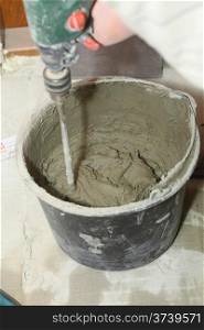 mixing Tile adhesive or cement with a power drill indoor construction