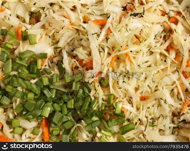 Mixture of ingredients for preparing a salad with finely chopped cabbage, carrots, dill and green onions close-up
