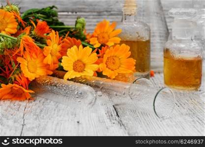 mixture of marigold. bottle of medicinal tincture of calendula flowers in folk recipe