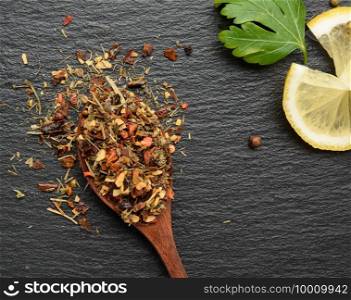 mixture of various dried spices in a wooden brown spoon, black background, close up