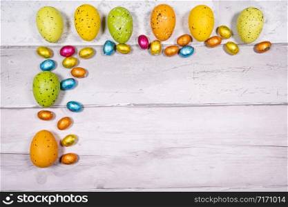 Mixtures of easter eggs of all colors and sizes on a background of old wooden boards resembling old parquet. Easter concept.. Mixtures of easter eggs of all colors and sizes on a background of old wooden boards resembling old parquet. Easter concept