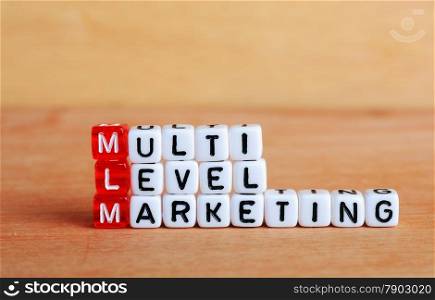 MLM Multi Level Marketing written on cubes wooden background