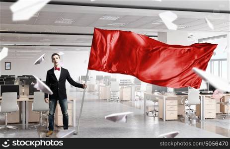 Mna waving red flag. Young businessman with red flag in office interior