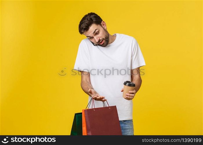 Mobile app for online shopping. Joyful happy man in casual white t-shirt holding cell phone and packages, smiling at camera. Mobile app for online shopping. Joyful happy man in casual white t-shirt holding cell phone and packages, smiling at camera.