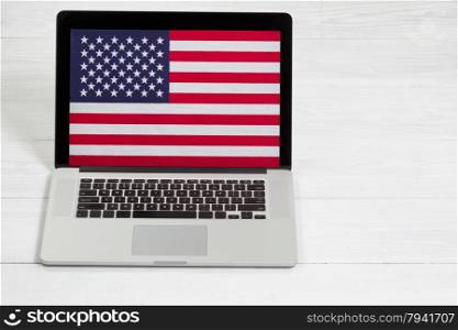 Mobile computer, United States of America flag on display screen, on white desktop. Concept of USA computer unsecured.