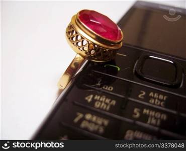 Mobile phone and golden ring with red stone