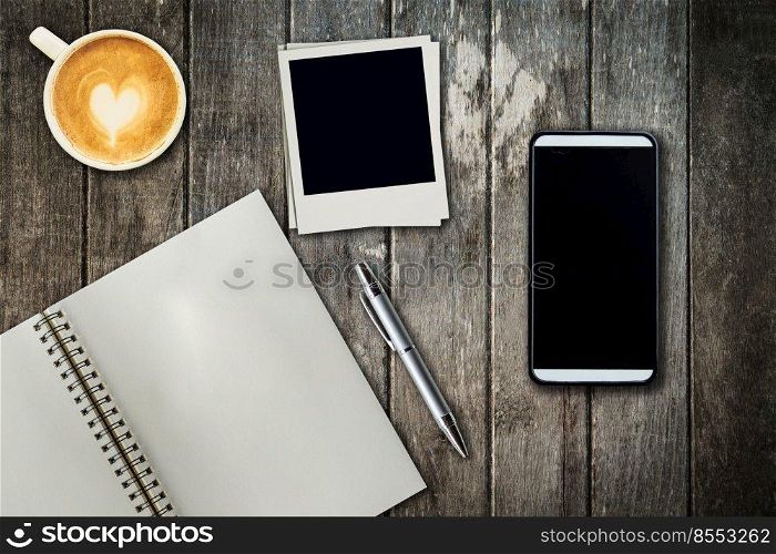 Mobile phone, notebook pen, photo frame and coffee cup on office wooden table with copy space.