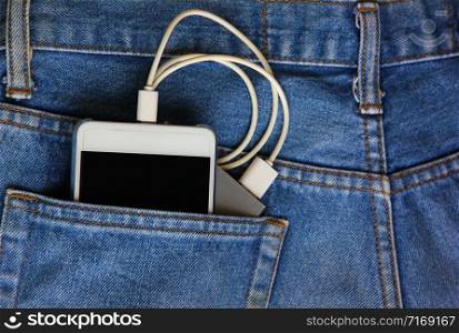 mobile phone with backup mobile battery in jean pocket.mobile phone is tranfer power from backup mobile battery.