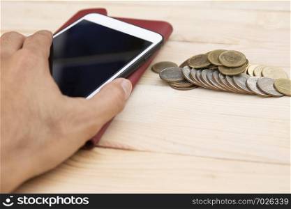 Mobile smart phone with coins on wood table